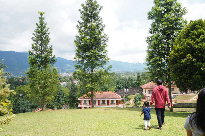 Ayah dan anak berjalan di lapangan terbuka dengan pemandangan gunung