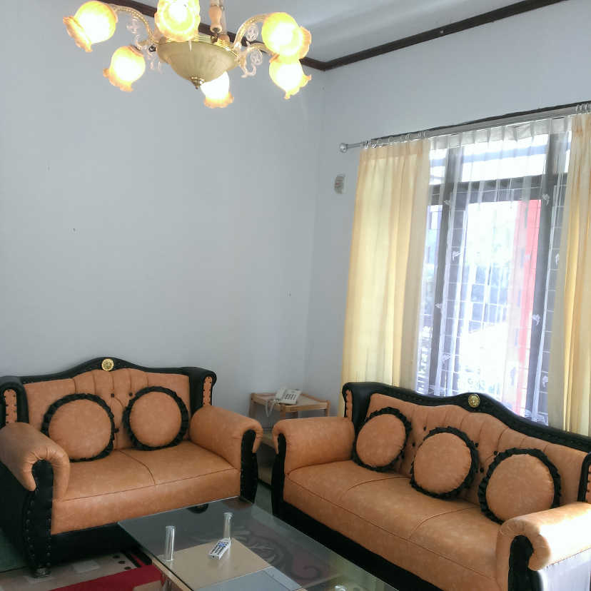 Set sofa kulit dan meja di ruang tamu dengan cahaya matahari dari jendela
